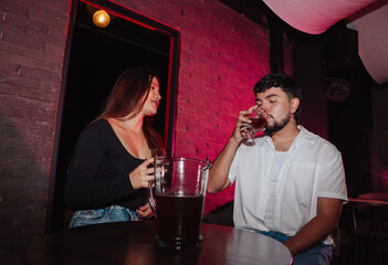 LGBT couple friends sitting and drinking beer in a bar happily