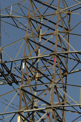 A detailed closeup image of a significant power transmission tower, prominently displayed against a vibrant blue sky in the background