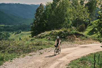 Cyclist on gravel road enjoying scenic mountain views.  Perfect for travel, adventure, and active...