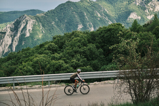 Cyclist rides gravel bike on scenic mountain road. Stunning landscape views. Perfect for travel, adventure, and active lifestyle concepts.