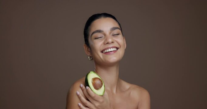 Face, skincare and woman with avocado, smile and natural cosmetic for anti aging, wellness and glow. Studio background, happy and person with fruit for dermatology, mockup space or treatment for skin
