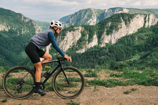 Female cyclist enjoys a scenic mountain bike ride. Stunning landscape with rolling hills and lush greenery provides a breathtaking backdrop. Perfect for active lifestyle, travel, and adventure themes.