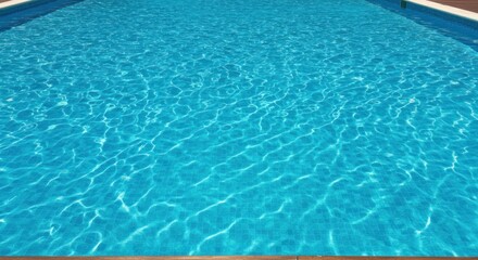 An overhead view of a swimming pool filled with clear, turquoise water, showing gentle ripples and sun reflections.