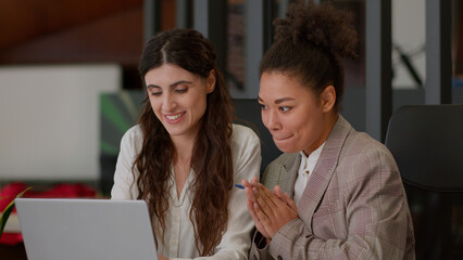 African American Caucasian female office coworkers happy cheerful girls ladies business partners businesswomen rejoice win online computer betting laptop screen multiracial women celebrate high five