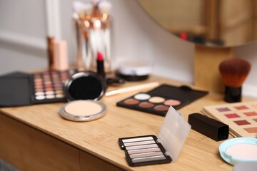 Different makeup products on wooden vanity indoors, closeup