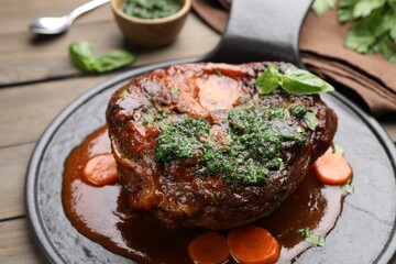 Traditional ossobuco dish with beef steak and sauce served on wooden table, closeup