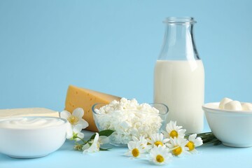 Fresh dairy products and flowers on light blue background, closeup