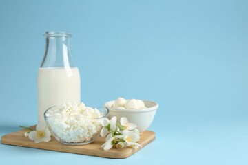 Fresh dairy products and jasmine flowers on light blue background. Space for text