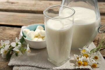 Fresh milk, mozzarella balls and flowers on wooden table, closeup. Dairy products