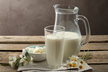 Fresh milk, mozzarella balls and flowers on wooden table, closeup. Dairy products