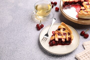 Piece of tasty cherry pie, berries and tea on grey textured table. Space for text