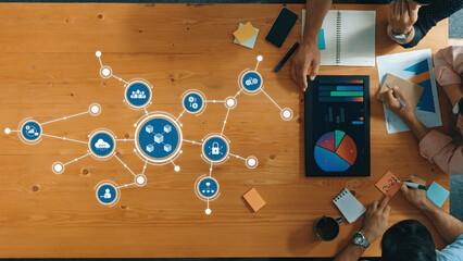 Engaging overhead view of a diverse group collaborating in a modern workspace, utilizing data visualization tools and charts to enhance business strategies and decision-making. Amity