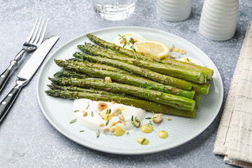 Tasty cooked asparagus served with lemon and sauce on grey table, closeup