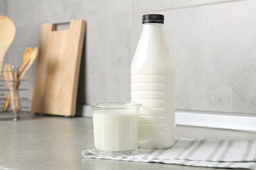 Dairy products. Fresh milk in glass and bottle on gray textured table indoors