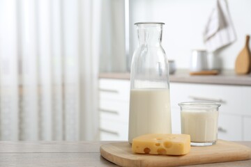 Dairy products. Fresh milk and cheese on wooden table in kitchen. Space for text