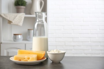 Different dairy products on gray textured table in kitchen. Space for text