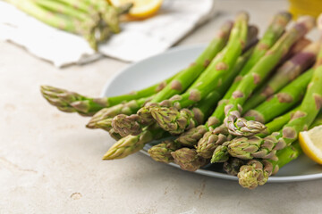 Fresh raw asparagus and lemon on light grey table, closeup