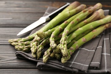 Fresh raw asparagus and knife on black wooden table, closeup