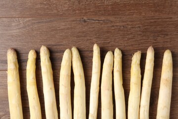 Raw white asparagus spears on wooden table, flat lay. Space for text