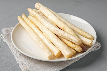 Raw white asparagus spears on grey textured table, closeup