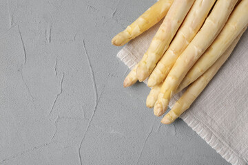Raw white asparagus spears on grey textured table, top view. Space for text