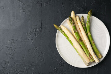 Green and white asparagus on black table, top view. Space for text