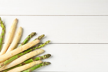 Different raw asparagus spears on white wooden table, flat lay. Space for text