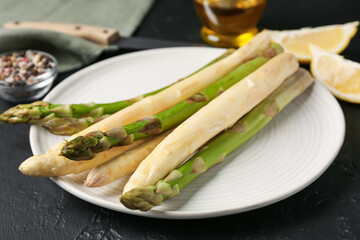 Green and white asparagus with spices on black table, closeup