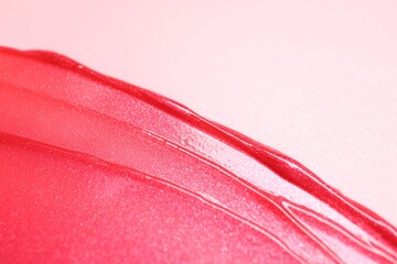 Sample of lip gloss on pink background, top view. Space for text