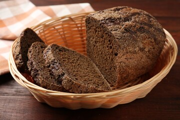 Pieces of fresh rye bread in wicker basket on wooden table, closeup