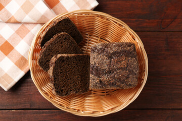 Pieces of fresh rye bread in wicker basket on wooden table, top view