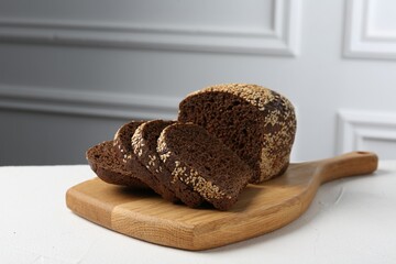 Pieces of fresh rye bread with seeds on white table against light grey wall, closeup