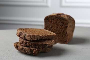 Pieces of fresh rye bread on light grey textured table, closeup