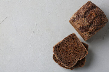 Pieces of fresh rye bread on light grey textured table, flat lay. Space for text