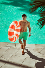 Man Walking By Pool With Inflatable Ring