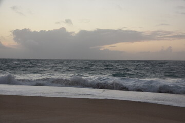 Waves crash onto the shore at Praia do Norte in Nazaré, Portugal, under a cloudy sunset sky—famous for its giant waves and dramatic ocean views.