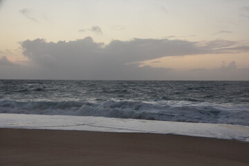 Waves crash onto the shore at Praia do Norte in Nazaré, Portugal, under a cloudy sunset sky—famous for its giant waves and dramatic ocean views.