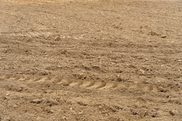Rows of soil before planting. Drawing of furrows on a plowed field prepared for spring sowing of agricultural crops. View of the land prepared for planting and growing crops.