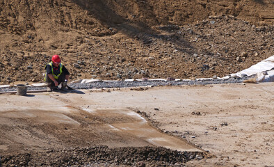 construction Worker Taking a Rest on Jobsite, Sitting on Ground During Workday Break
