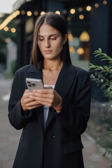 Business woman holding smartphone at city street