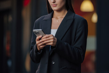 Hands of business woman using smartphone at city street