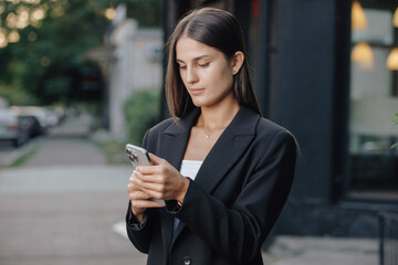 Business woman using smartphone at city street