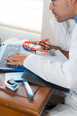 Vertical shot of professional doctor writes on the computer in an organized medical office manifesting healthcare and technology integration for modern diagnostics.