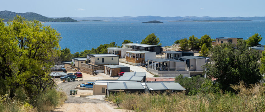 A stunning coastal vista marred by the architectural ugliness of haphazardly scattered mobile homes, their mismatched designs clashing with the superb natural beauty of the sea and hills. A chaotic