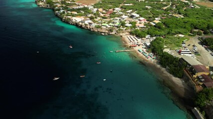 Drone shot flying above colorful water at Playa Piskado with beachline and sunbeds.
Ideal for travel vlogs, real estate near beaches, resort ads.