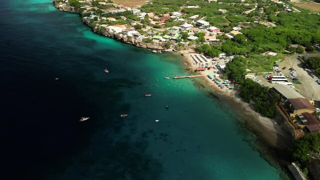Drone shot flying above colorful water at Playa Piskado with beachline and sunbeds.
Ideal for travel vlogs, real estate near beaches, resort ads.