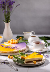 Delicious lavender cheesecake with yellow raspberries and cup of tea on table