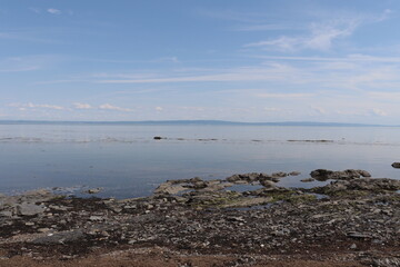 Rocks formation on a beach in Charlevoix in Quebec. Peaceful and zen atmosphere with a vast river and a beautiful riverside. Horizon and coastline. Charlevoix landscape in summer. Low tide.