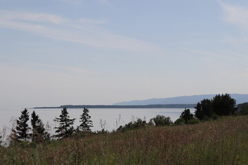 A view of the St-Laurent river in Carlevoix in Quebec in Canada. Charlevoix landscape. Zen and peaceful atmosphere. A view of a riverside and a bay with trees. Horizon and distant.
