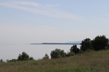 A view of the St-Laurent river in Carlevoix in Quebec in Canada. Charlevoix landscape. Zen and peaceful atmosphere. A view of a riverside and a bay with trees. Horizon and distant.